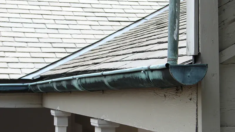 Copper gutter and downspout under the slate roof of an older house
